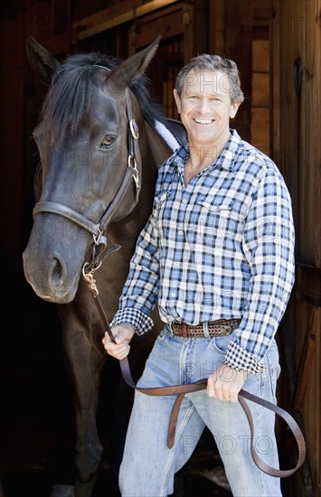 Caucasian man holding horse's bridle