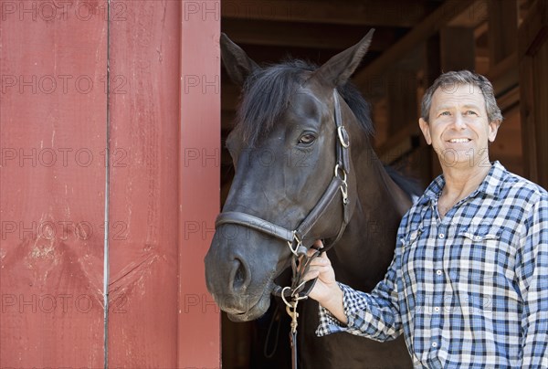 Caucasian man holding horse's bridle