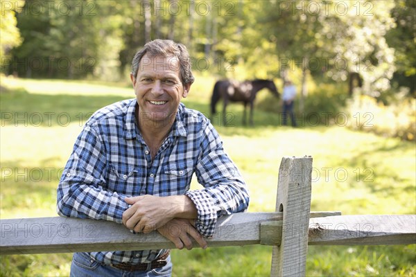 Caucasian man leaning on wooden fence