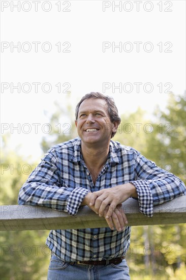 Caucasian man leaning on wooden fence