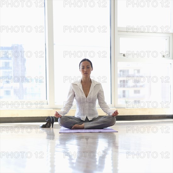 Asian businesswoman practicing yoga on office floor
