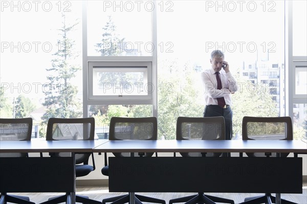 Caucasian businessman using cell phone in conference room