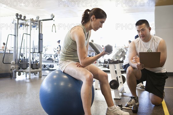 Woman working with personal trainer in health club