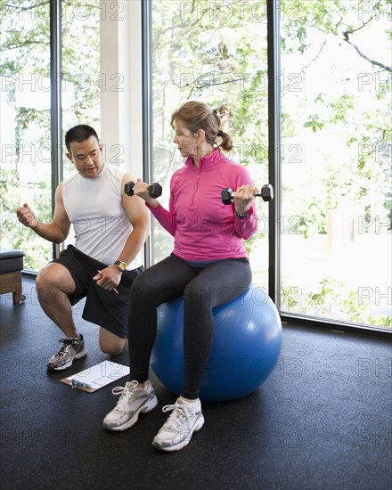 Woman working with personal trainer in health club