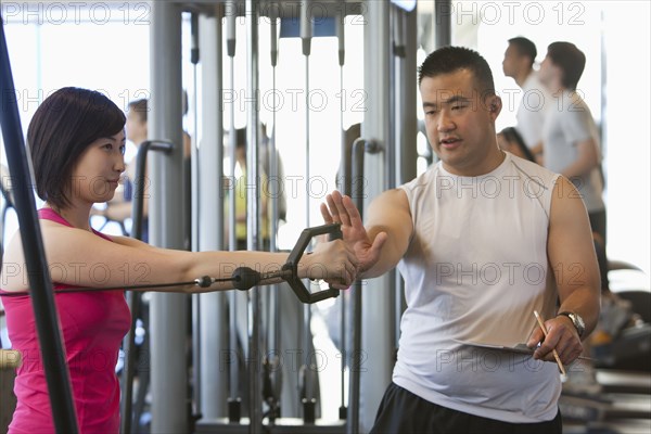 Woman working with personal trainer in health club