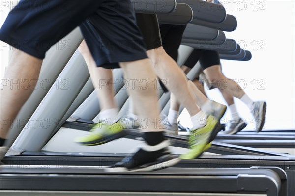 People running on treadmills in health club