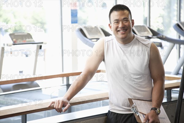 Smiling man with clipboard standing in health club