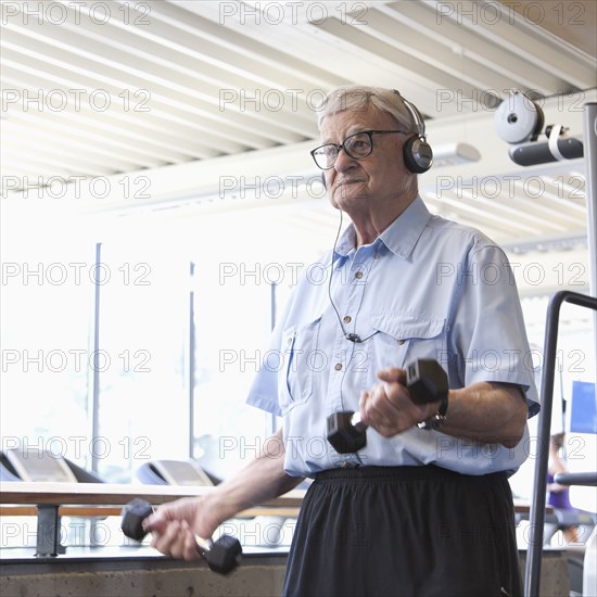 Senior man lifting weights in health club