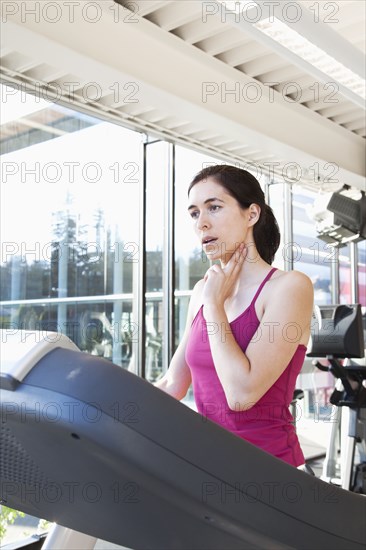 Woman on treadmill checking her pulse