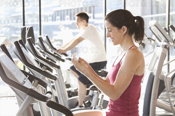 Woman on treadmill text messaging on cell phone