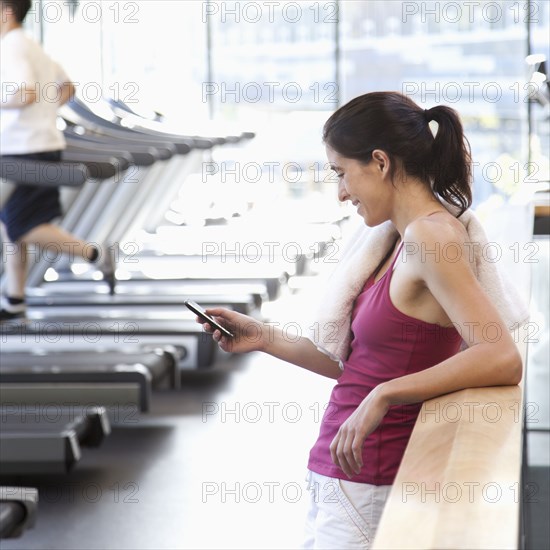 Woman text messaging on cell phone in health club