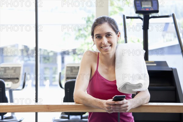 Woman holding cell phone in health club
