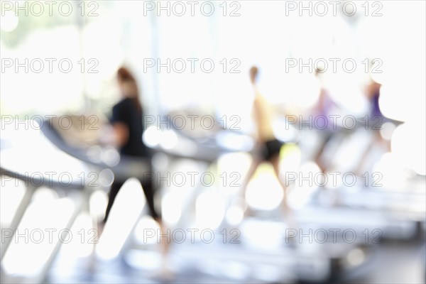 Defocused view of people on treadmills in health club