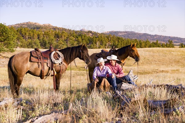 Caucasian couple relaxing in field with horses
