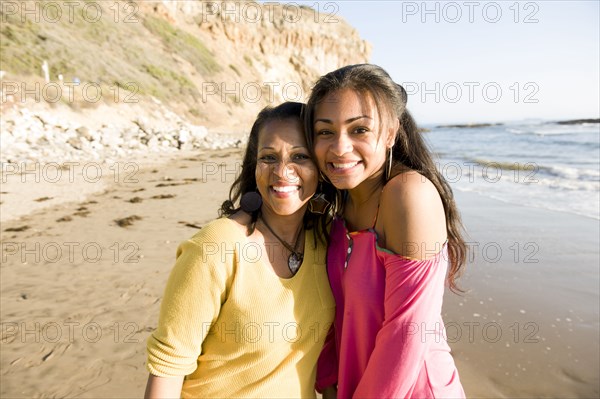 African American mother and daughter smiling on beach