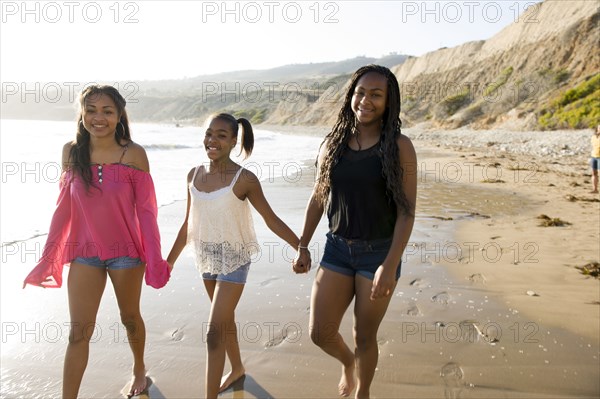 African American sisters holding hands on beach