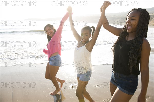 African American sisters holding hands on beach