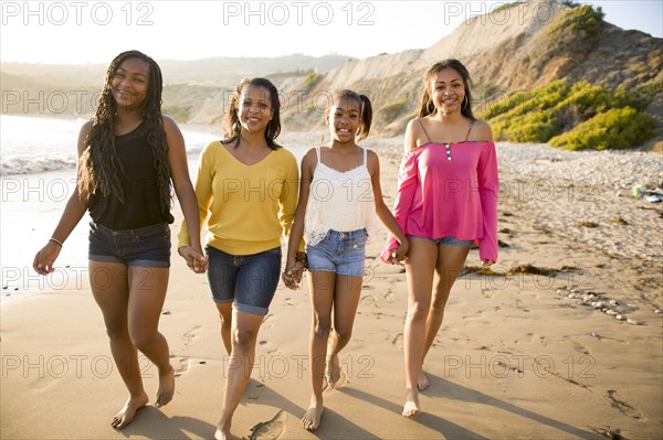 African American mother and daughters walking on beach
