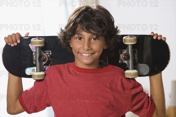 Mixed Race boy holding skateboard