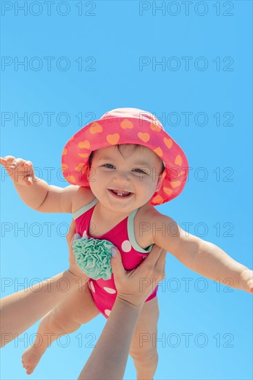 Woman holding baby girl against blue sky