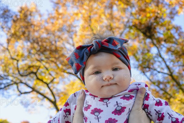 Woman holding baby girl against autumn tree