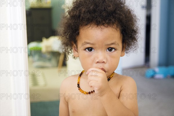 Naked Mixed Race baby boy sucking thumb