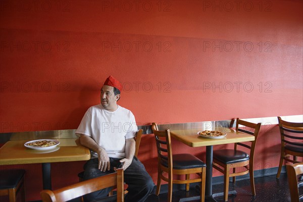 Chef sitting at table in pizzeria