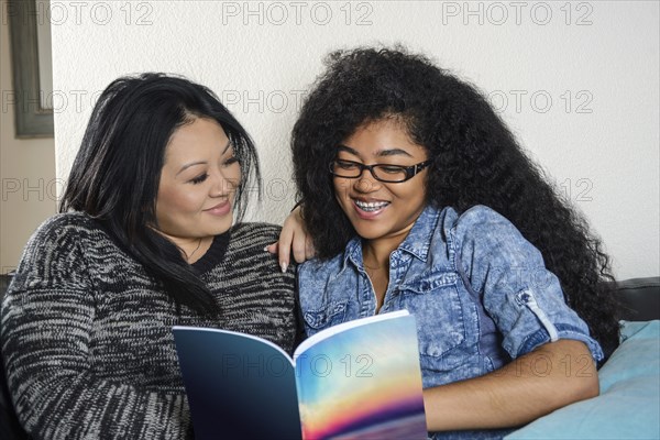 Smiling mother and daughter reading book