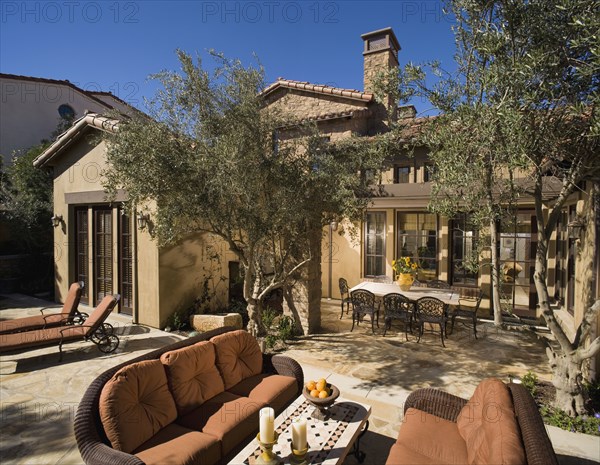 Rear exterior of Tuscan home with sitting and dining areas