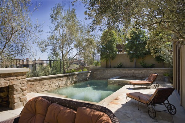 Tuscan style back yard with swimming pool and lounge chairs