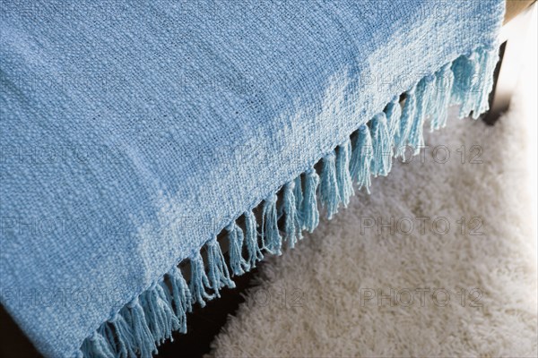 Blue throw blanket with tassels hanging over chair