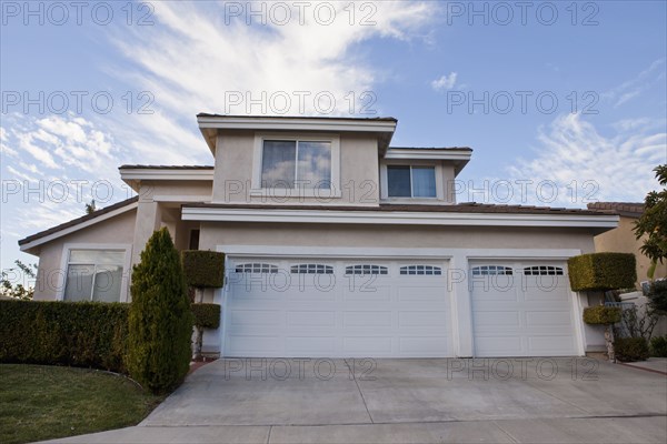 Exterior of middle class home with garages and driveway