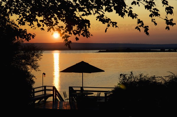 Deck silhouetted against lake at sunset