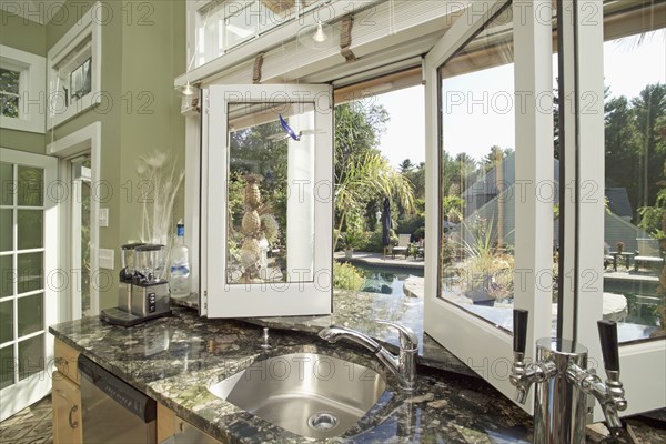 Sink on granite counter by open window in domestic kitchen