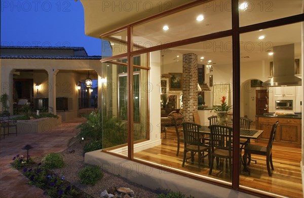 Exterior view looking through picture windows into kitchen and dining room