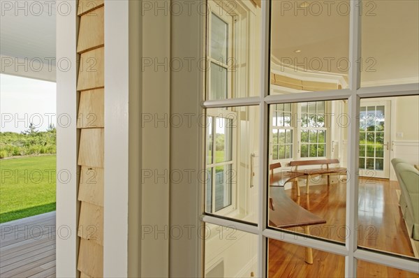 View from outside into sunroom with row of wooden benches