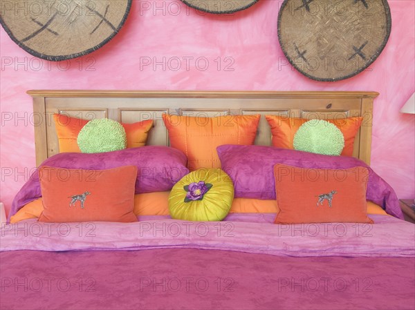 Pink and orange throw pillows on bed