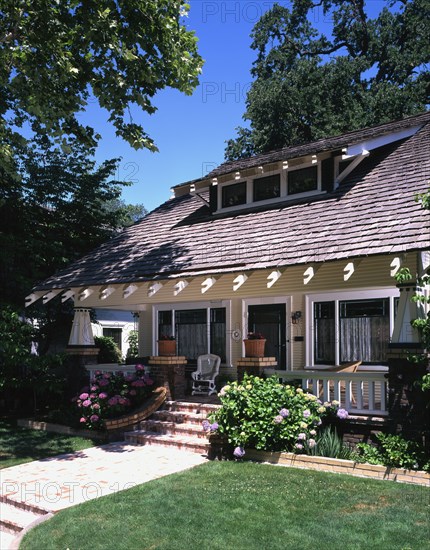 Front exterior view of a yellow craftsman house with white trim