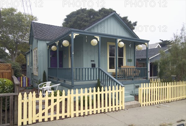 Exterior green American Craftsman styled bungalow with yellow fence