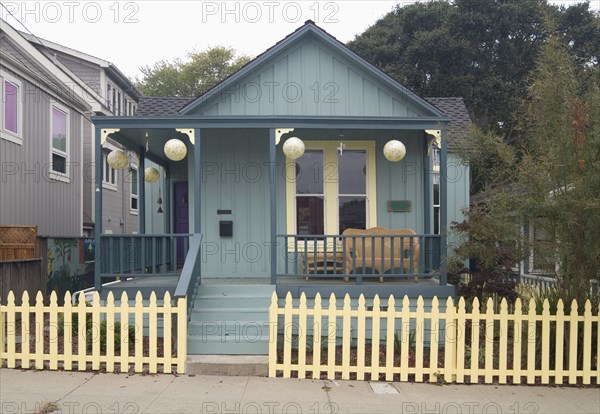 Exterior green American Craftsman styled bungalow with yellow fence