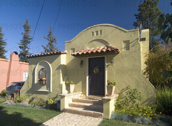 Front exterior one story Spanish style house with potted plants