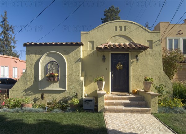 Front exterior one story Spanish style house with potted plants