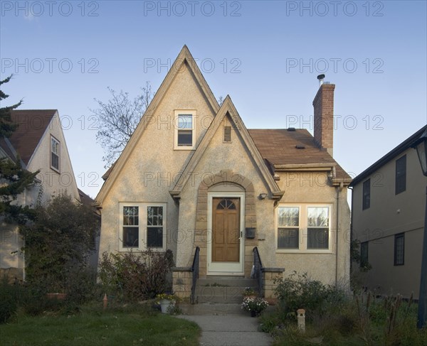 Exterior view of a beige cottage with angled roof tops