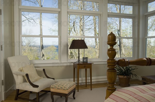 Detail bedroom with several windows and armchair