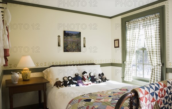 Small colonial bedroom with collection of amish dolls on bed