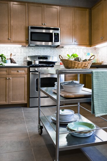 Stacks of dishes on chefs cart in domestic kitchen