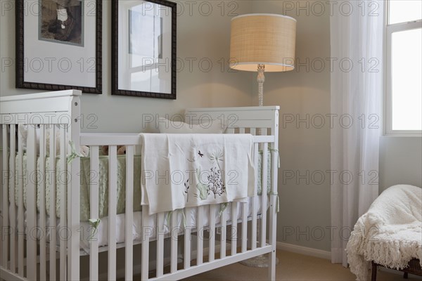 Baby's crib with floor lamp and picture frames in the house