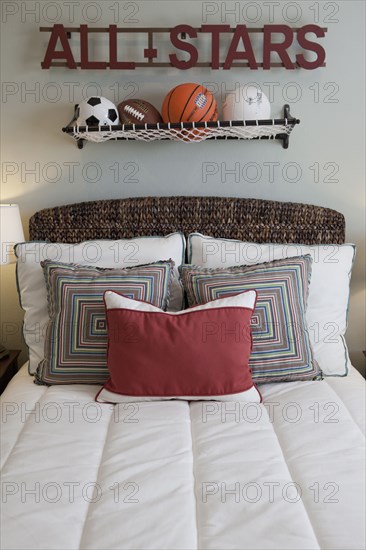 Balls over arranged pillows on tidy bed in the bedroom at home