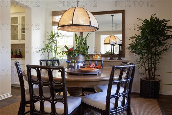 Chairs at round dining table below lit hanging light at home