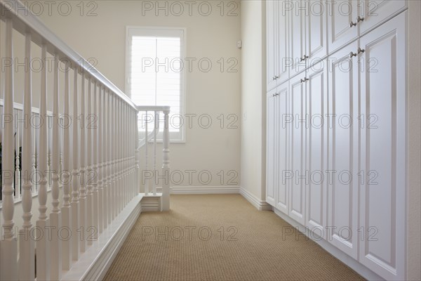 White railings and cabinets along hallway at home